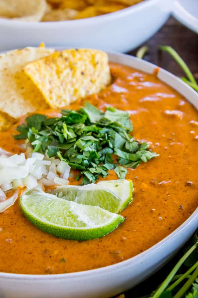copycat chili's queso dip with chips, limes, cilantro, and onions on top.