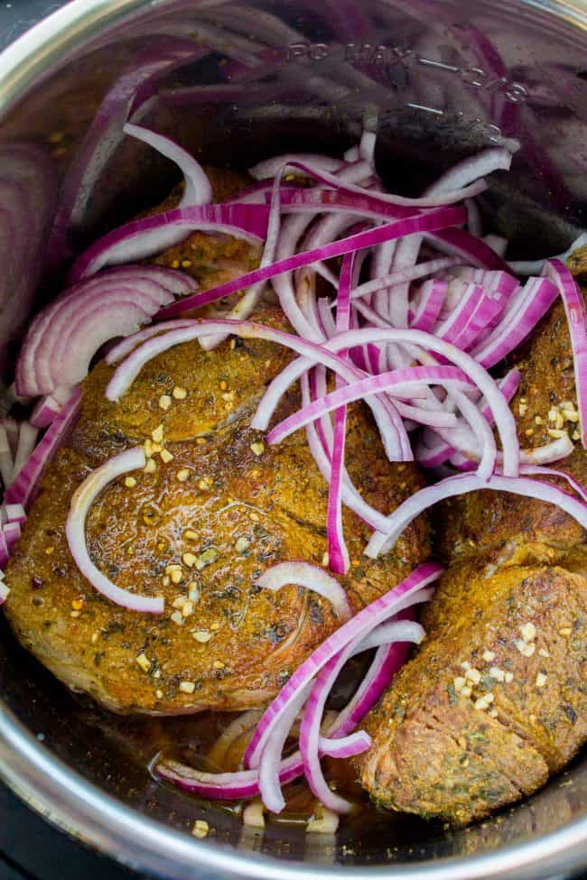 Gyro Style Shredded Beef (Instant Pot or Crock Pot) from The Food Charlatan. All the gyro flavors you love, shredded beef style! This is a super delicious and HEALTHY option for dinner. Make it in the Instant Pot or the Crock Pot! Don't forget to pair it with Tzatziki Sauce (<<it's killer) and Cauliflower Rice. #gyro #gyromeat #beef #shreddedbeef #slowcooker #crockpot #pressurecooker #instantpot #healthy #paleo #whole30 #Greek #pita #rice #tzatziki #sauce #easy beef roast, browned and rubbed with spices, in the Instant Pot with sliced red onions.