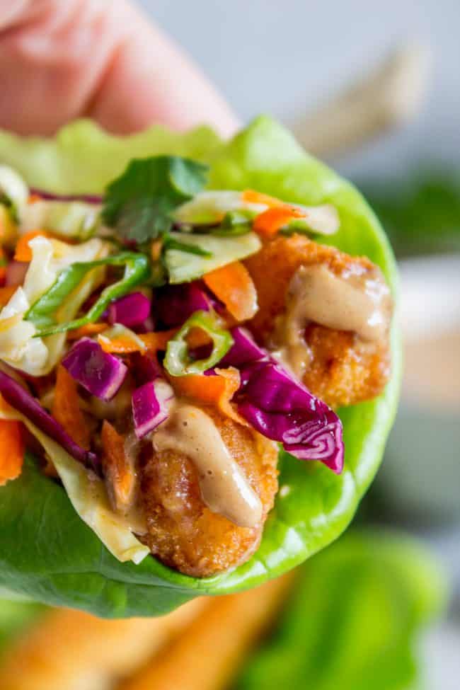 Thai Lettuce Wraps with Crispy Fish and Peanut Sauce from The Food Charlatan. These are a fabulous way to start off your January! Supple butter lettuce wrapped around crispy baked fish, topped with a gingery homemade Asian slaw. Drizzle with sweet and spicy Thai Peanut Sauce and you have an easy and healthy Asian-inspired weeknight dinner! #healthy #fish #crispy #cabbage #slaw #asian #Thai #peanutsauce #easy #sauce #lowcarb #lunch #simple #butterlettuce #greenonion #carrot #purplecabbage Thai lettuce wraps.