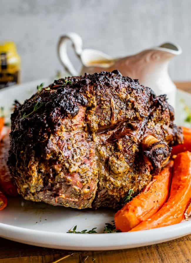 Roast Leg of Lamb with Blackened Honey Dijon Crust from The Food Charlatan. #ad #OhMaille #MyMaille #IDidItMailleWay Roast leg of lamb makes an unforgettable main dish for your Easter celebration! Roast lamb is so delicious, moist, and tender when it is done right. The secret is to turn the oven to 500 degrees to get that blackened honey dijon crust made with Maille® Honey Dijon, then lower it to get the most tender, juicy roast lamb you've ever had. #Walmart #leg #recipes #dinner #easter #lamb roast leg of lamb with carrots and a gravy boat.