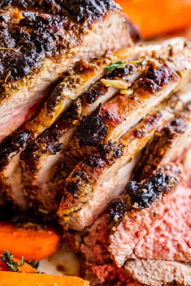 Roast Leg of Lamb with Blackened Honey Dijon Crust from The Food Charlatan. #ad #OhMaille #MyMaille #IDidItMailleWay Roast leg of lamb makes an unforgettable main dish for your Easter celebration! Roast lamb is so delicious, moist, and tender when it is done right. The secret is to turn the oven to 500 degrees to get that blackened honey dijon crust made with Maille® Honey Dijon, then lower it to get the most tender, juicy roast lamb you've ever had. #Walmart #leg #recipes #dinner #easter #lamb roast lamb sliced with cooked carrots.