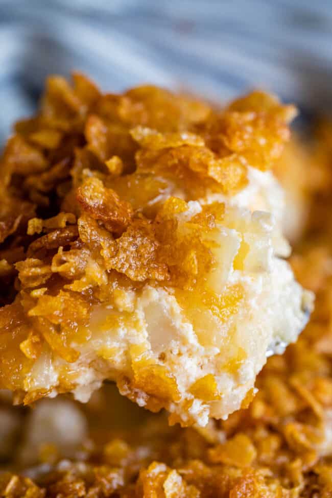 Close-up of creamy funeral potatoes, topped with a golden, crispy layer of cornflakes, showing a crunchy texture and melted cheese.