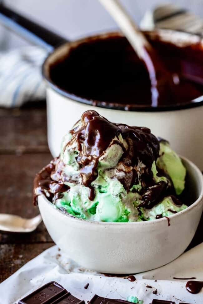 Homemade Chocolate Sauce (The Only Hot Fudge Sauce You'll Ever Need) from The Food Charlatan. Once you go homemade, there's NO going back! This recipe is super easy, uses pantry ingredients, and takes 15 minutes. It's 10x better than store bought hot fudge sauce. It's creamy, smooth, and so chocolatey. #hotfudge #fudge #hot #icecream #Toppings #sauce #homemade #recipe #chocolate #Chocolatesauce #easy #desserts #sundae #uses #oldfashioned #withevaporatedmilk #best #topping #nocornsyrup homemade chocolate sauce on ice cream in a white bowl.