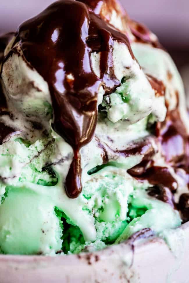 Homemade Chocolate Sauce (The Only Hot Fudge Sauce You'll Ever Need) from The Food Charlatan. Once you go homemade, there's NO going back! This recipe is super easy, uses pantry ingredients, and takes 15 minutes. It's 10x better than store bought hot fudge sauce. It's creamy, smooth, and so chocolatey. #hotfudge #fudge #hot #icecream #Toppings #sauce #homemade #recipe #chocolate #Chocolatesauce #easy #desserts #sundae #uses #oldfashioned #withevaporatedmilk #best #topping #nocornsyrup hot fudge sauce on mint chocolate chip ice cream.