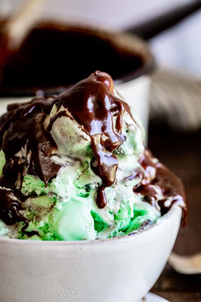 Homemade Chocolate Sauce (The Only Hot Fudge Sauce You'll Ever Need) from The Food Charlatan. Once you go homemade, there's NO going back! This recipe is super easy, uses pantry ingredients, and takes 15 minutes. It's 10x better than store bought hot fudge sauce. It's creamy, smooth, and so chocolatey. #hotfudge #fudge #hot #icecream #Toppings #sauce #homemade #recipe #chocolate #Chocolatesauce #easy #desserts #sundae #uses #oldfashioned #withevaporatedmilk #best #topping #nocornsyrup chocolate sauce on mint ice cream.