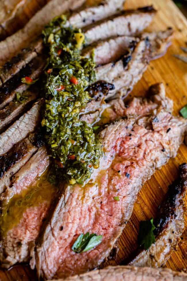 How to Cook Flank Steak (Grilled or Oven Broiled) from The Food Charlatan. Flank Steak is incredibly tasty when done well, but can be really easy to mess up. I will show you all my tips to get a flavorful, juicy, and tender flank steak, grilled outside or under the broiler! Using a great marinade, slicing correctly, and cooking hot and fast are the secrets to a fabulous flank steak. #flank #flanksteak #steak #beef #grill #grilled #easy #recipe #summer #marinade #oven #howtocook #chimichurri sliced grilled flank steak with chimichurri sauce.