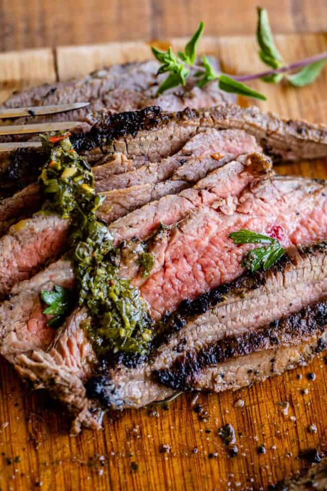 How to Cook Flank Steak (Grilled or Oven Broiled) from The Food Charlatan. Flank Steak is incredibly tasty when done well, but can be really easy to mess up. I will show you all my tips to get a flavorful, juicy, and tender flank steak, grilled outside or under the broiler! Using a great marinade, slicing correctly, and cooking hot and fast are the secrets to a fabulous flank steak. #flank #flanksteak #steak #beef #grill #grilled #easy #recipe #summer #marinade #oven #howtocook #chimichurri flank steak on a wooden cutting board with chimchurri sauce.