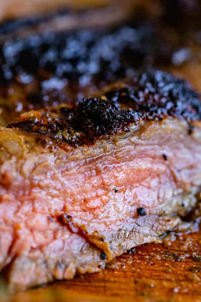 How to Cook Flank Steak (Grilled or Oven Broiled) from The Food Charlatan. Flank Steak is incredibly tasty when done well, but can be really easy to mess up. I will show you all my tips to get a flavorful, juicy, and tender flank steak, grilled outside or under the broiler! Using a great marinade, slicing correctly, and cooking hot and fast are the secrets to a fabulous flank steak. #flank #flanksteak #steak #beef #grill #grilled #easy #recipe #summer #marinade #oven #howtocook #chimichurri perfectly cooked juicy flank steak on a wooden cutting board.