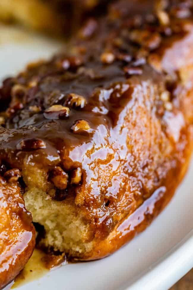 pecan cinnamon rolls with caramel sauce dripping over the side.