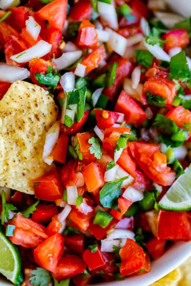 How to Make Authentic Pico de Gallo from The Food Charlatan. Learn how to make the best Pico de Gallo! It's a very simple Mexican salsa with tomatoes, onions, jalapeno, cilantro, and lime juice. Humble ingredients come together to make one of the best appetizers of all time! You will never look at tacos the same after topping them with this magical stuff. #picodegallo #salsa #Mexican #cold #fresh #appetizer #dip #forparties #easy #recipe #receta #authentic #best #homemade #restaurant #picodegalo pico de gallo with tortilla chips.