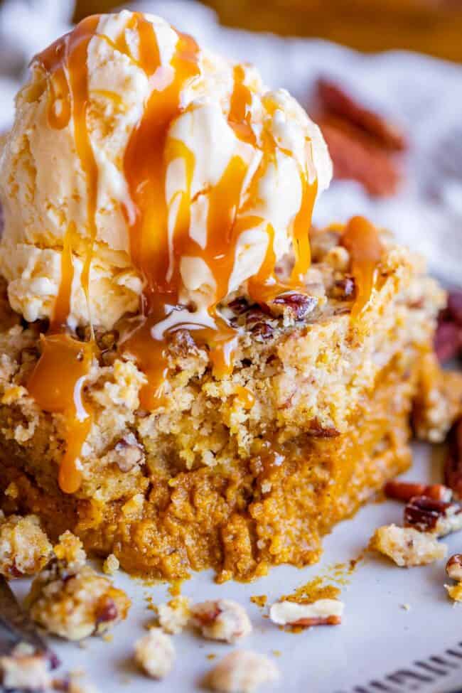 slice of pumpkin dump cake with ice cream and caramel sauce on top.