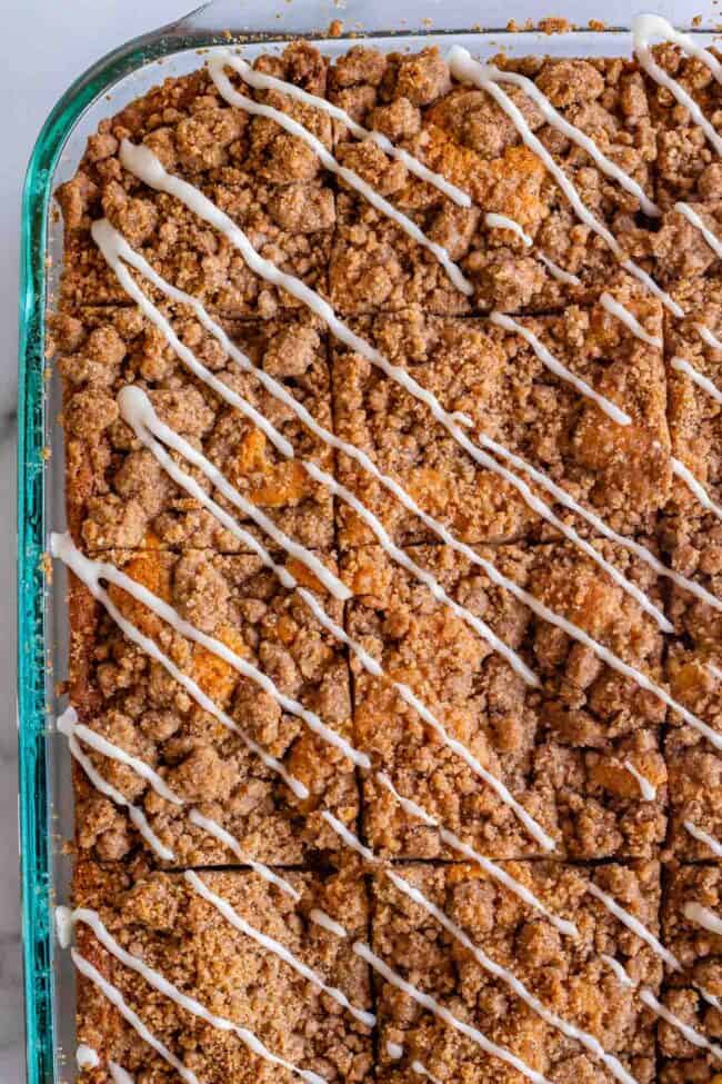 Sour Cream Coffee Cake, with a Ridiculous Amount of Streusel from The Food Charlatan. This is my FAVORITE recipe for Sour Cream Coffee Cake! My main complaint with Coffee Cake is that there is usually too much cake, not enough streusel. This recipe gives you the max amount of streusel without ruining the light fluffiness of the cake! A vanilla drizzle finishes it off! #coffeecake #sourcream #icing #frosting #drizzle #easy #recipes #cinnamon #streusel #sourcream #crumb #crumble #moist #breakfast Streusel coffee cake in a 9x13 inch pan with diagonal drizzles of vanilla icing.