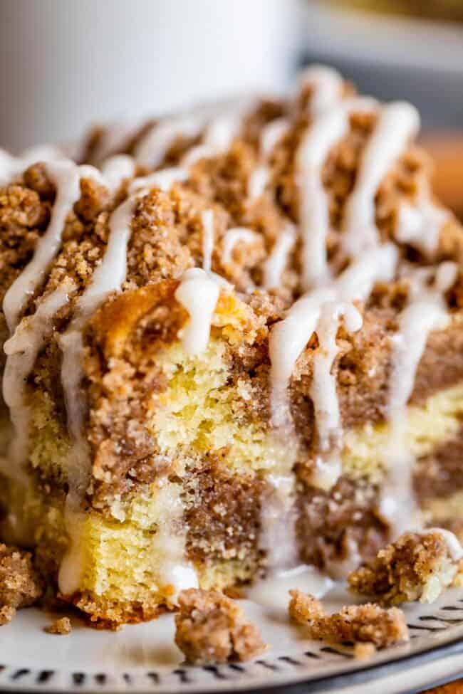 Sour Cream Coffee Cake, with a Ridiculous Amount of Streusel from The Food Charlatan. This is my FAVORITE recipe for Sour Cream Coffee Cake! My main complaint with Coffee Cake is that there is usually too much cake, not enough streusel. This recipe gives you the max amount of streusel without ruining the light fluffiness of the cake! A vanilla drizzle finishes it off! #coffeecake #sourcream #icing #frosting #drizzle #easy #recipes #cinnamon #streusel #sourcream #crumb #crumble #moist #breakfast cinnamon streusel coffee cake with vanilla glaze shot up close.