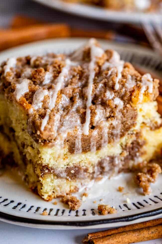 Sour Cream Coffee Cake, with a Ridiculous Amount of Streusel from The Food Charlatan. This is my FAVORITE recipe for Sour Cream Coffee Cake! My main complaint with Coffee Cake is that there is usually too much cake, not enough streusel. This recipe gives you the max amount of streusel without ruining the light fluffiness of the cake! A vanilla drizzle finishes it off! #coffeecake #sourcream #icing #frosting #drizzle #easy #recipes #cinnamon #streusel #sourcream #crumb #crumble #moist #breakfast slice of sour cream coffee cake drizzled with vanilla icing.