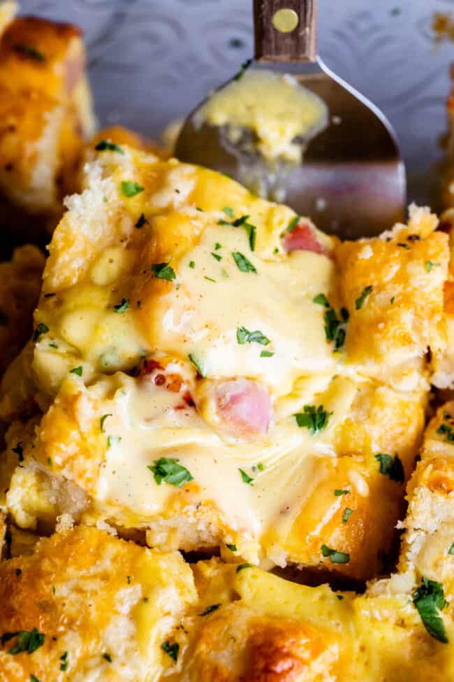 Cheesy Ham and Egg Breakfast Casserole with Biscuits from The Food Charlatan. This crowd-pleasing casserole is my new favorite! Use store bought or homemade biscuits to make a moist and delicious brunch. Top it all off with Hollandaise Sauce for an amazing holiday breakfast! #breakfast #brunch #ham #bacon #sausage #easy #recipe #holidays #Thanksgiving #Christmas #makeahead #withbiscuits #overnight #recipes #foracrowd #best #nightbefore #simple #quick #forlargegroups #Pillsbury #freezer #savory ham and cheese breakfast casserole made with biscuits and topped with hollandaise.