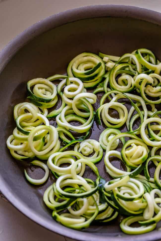 curly zoodles in a frying pan. 