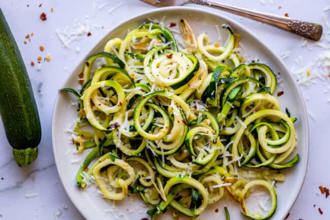 zucchini noodles on a white plate with a fork.