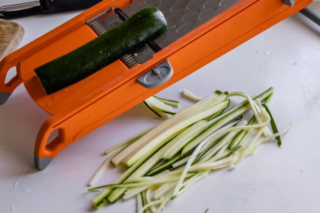 using a mandolin to make straight zucchini noodles.