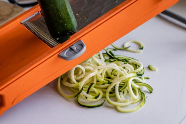 using a mandoline to make zucchini noodles.