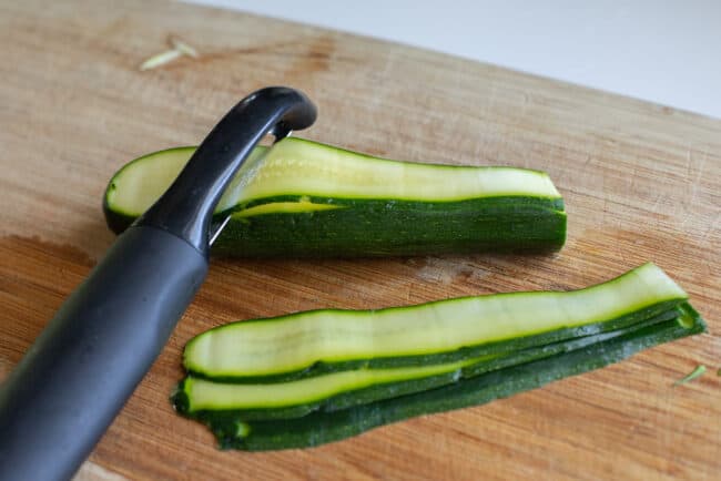 peeling zucchini into ribbons using a vegetable peeler.