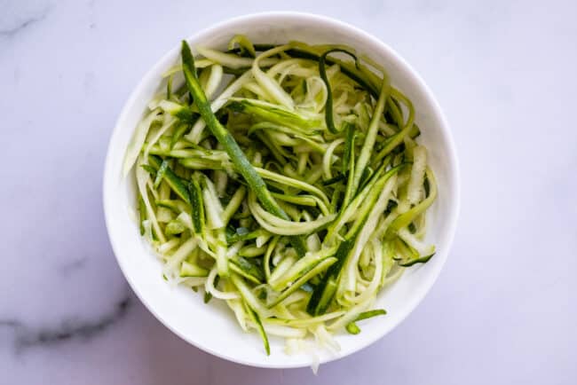 straight zoodles in a white bowl on a counter.