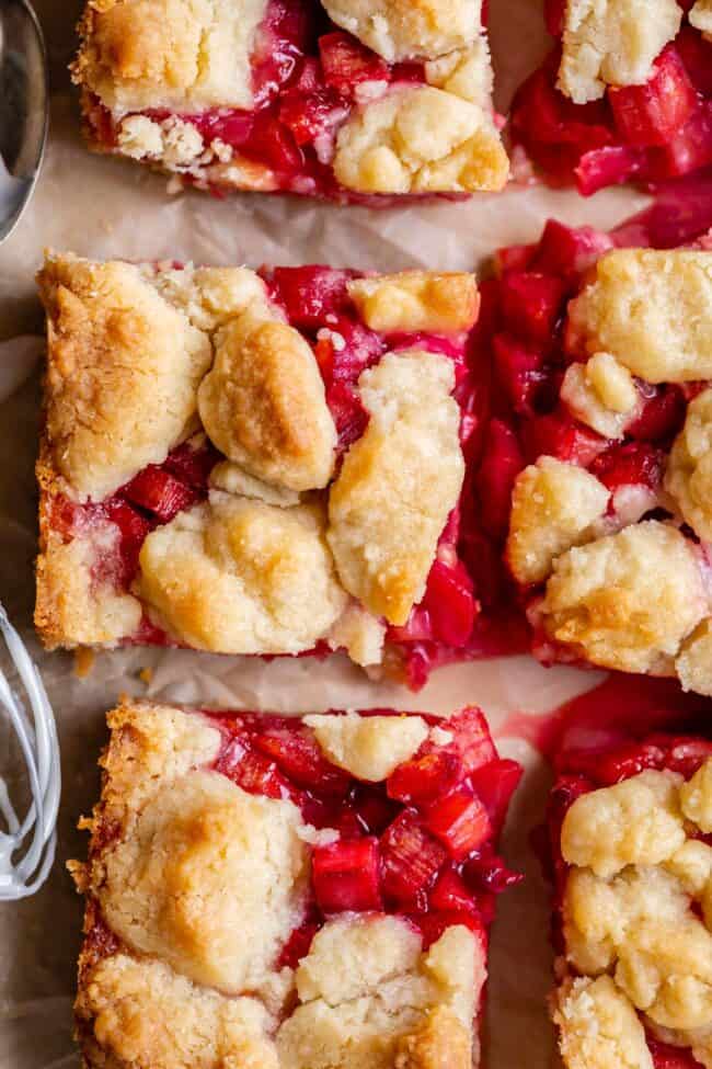 Rhubarb Shortbread Bars from The Food Charlatan. Rhubarb Shortbread Bars are a dream come true! A thick and buttery shortbread crust, topped with a layer of simple rhubarb filling, and topped with even more glorious shortbread. There is a secret ingredient in this recipe that makes these rhubarb bars bright ruby red, and it's not food coloring. It works like a charm! #easy #recipe #rhubarb #shortbread #butter #bars #dessert #withoutstrawberry #recipe #shortbreadcrust #lemon #best #pie rhubarb dessert bars in squares