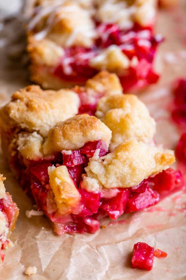 Rhubarb Shortbread Bars from The Food Charlatan. Rhubarb Shortbread Bars are a dream come true! A thick and buttery shortbread crust, topped with a layer of simple rhubarb filling, and topped with even more glorious shortbread. There is a secret ingredient in this recipe that makes these rhubarb bars bright ruby red, and it's not food coloring. It works like a charm! #easy #recipe #rhubarb #shortbread #butter #bars #dessert #withoutstrawberry #recipe #shortbreadcrust #lemon #best #pie rhubarb bars with a golden top sowing off the shortbread crust recipe