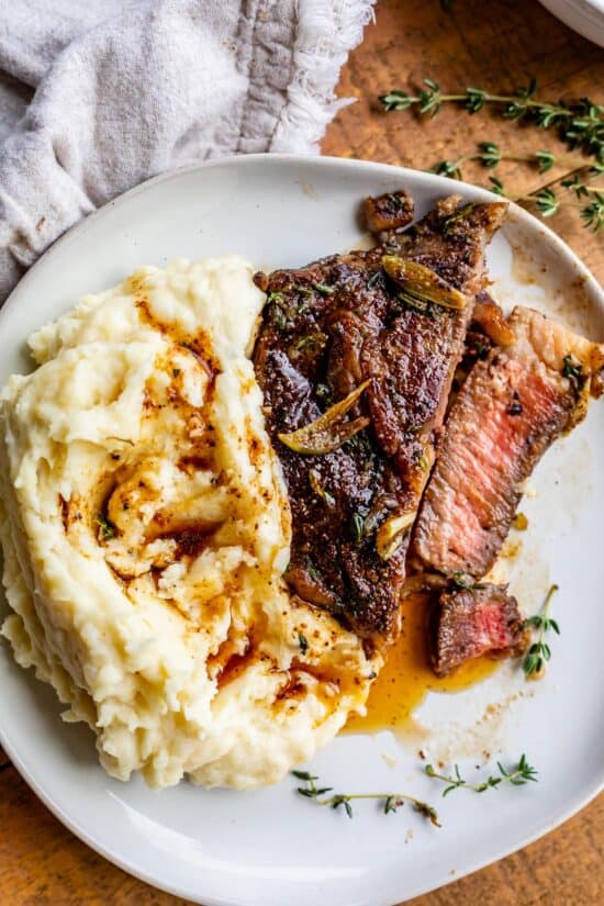 rib eye steak on plate in slices next to mashed potatoes