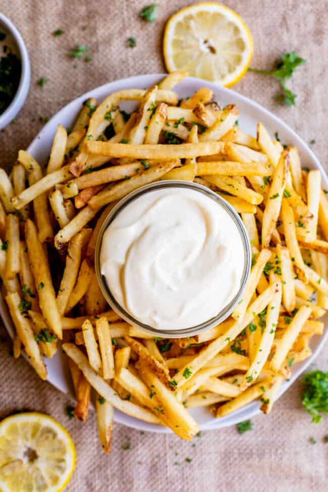 garlic aioli sauce in a jar with a plate of fries.