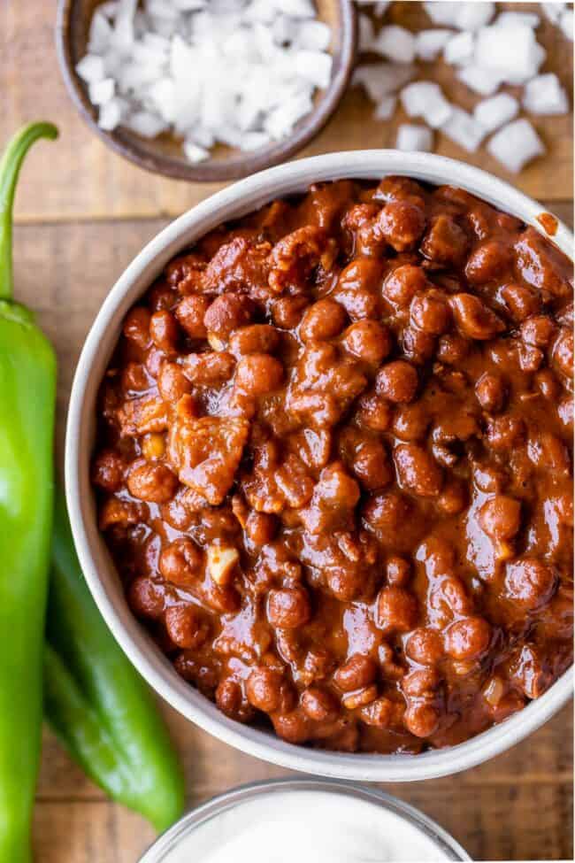 Santa Maria Pinquito Beans from The Food Charlatan. These Santa Maria style Pinquito Beans are the perfect summer barbecue side dish! Originally created in Santa Maria, California to be served alongside Grilled Tri Tip, these beans are smokey and sweet with the perfect blend of spices. Eat them with tri tip or serve alongside whatever else you're barbecuing this summer! #easy #recipe #bbq #barbecue #beans #bakedbeans #santamaria #tritip #sidedish #bacon #pinquito #creamy #summer #onion #anaheim pinquito beans with anaheim peppers and chopped onions.