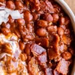 santa maria style beans in a bowl with bacon and sour cream