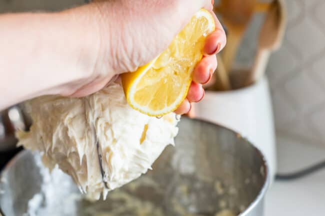 squeezing lemon juice into a stand mixer full of frosting.