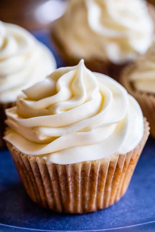 homemade cream cheese frosting on a cupcake on a blue plate.