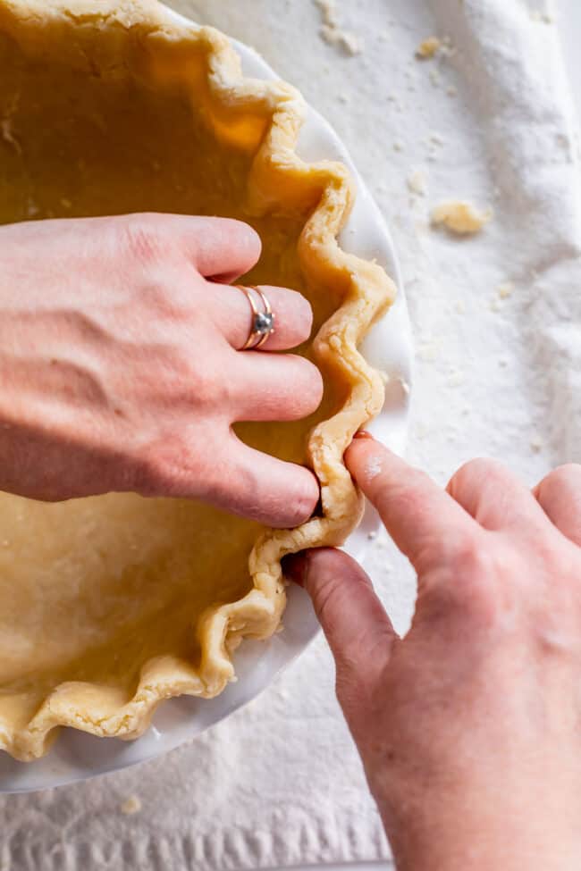 fluting the edges of pie crust to blind bake.