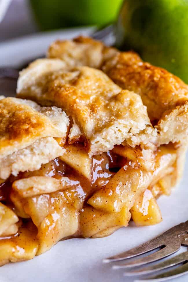 slice of apple pie with homemade flaky pie crust next to a metal fork.