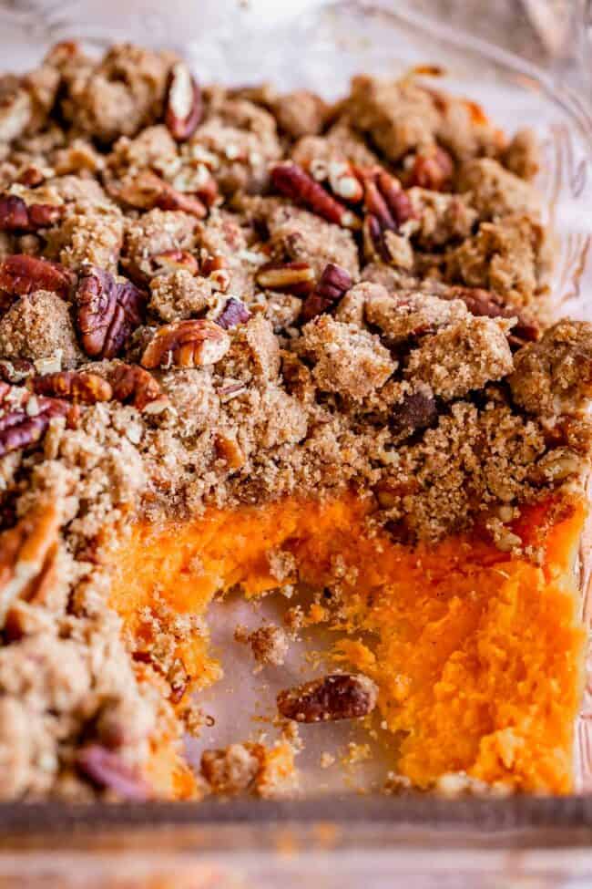 sweet potato casserole with pecans in a glass pan with sweet potatoes exposed.