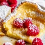 German pancake recipe with raspberries, syrup, and powdered sugar