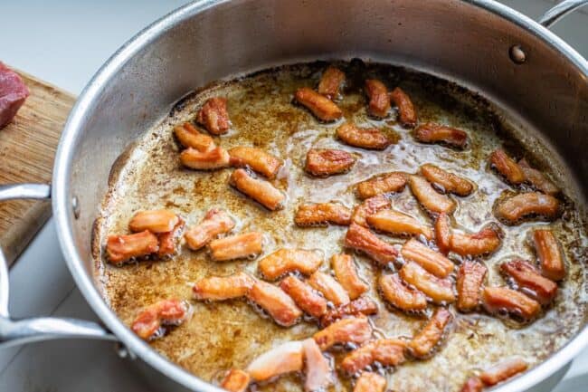 salt pork being fried in a pan for beef bourguignon.