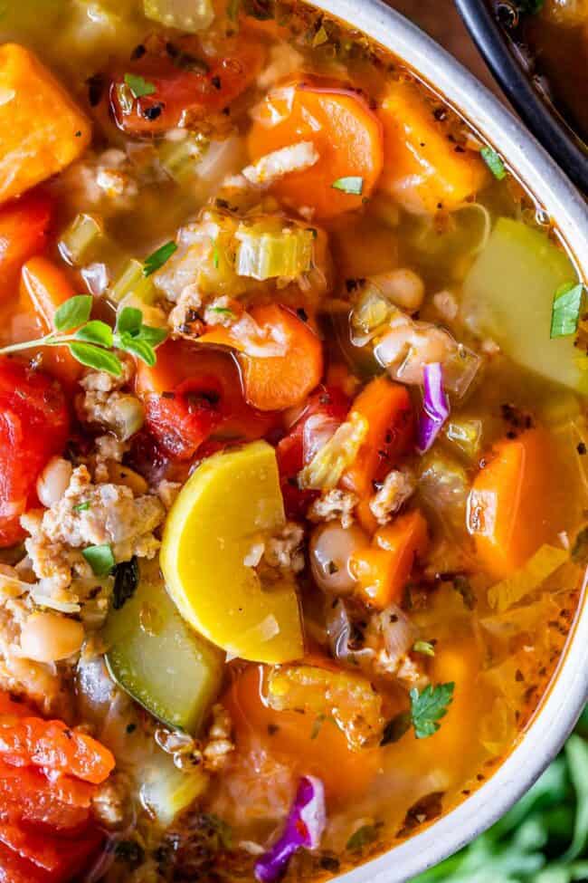 close up overhead shot of turkey weight loss soup in a white bowl with fresh herbs.