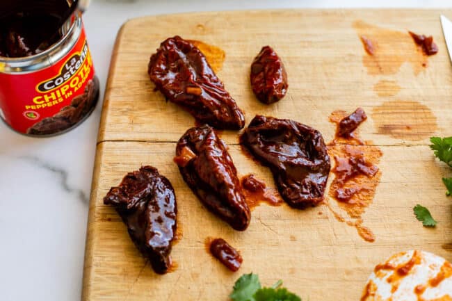 chipotle peppers laid out on a wooden cutting board.