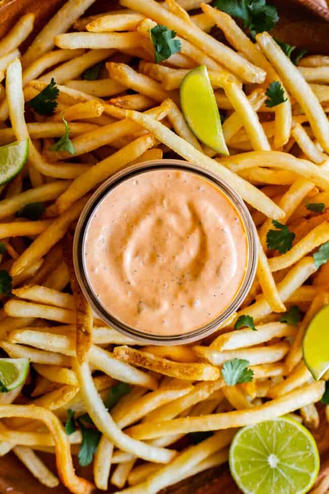 chipotle mayo recipe in a jar surrounded by fries and lime slices.