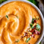 thai peanut sauce recipe in a bowl sprinkled with cilantro, dried chili, and cucumbers on the side