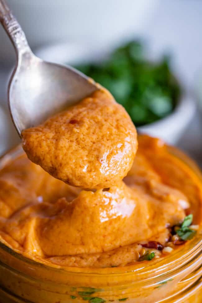 easy Thai peanut sauce in a jar being lifted with a spoon.