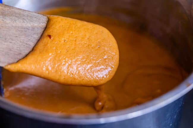 Thai peanut sauce on a wooden spoon in a saucepan.