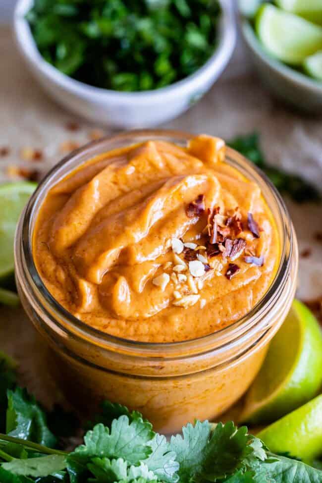 spicy Thai peanut sauce in a jar with ingredients around it.