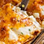 scalloped potatoes with cheese being lifted out of the pan with a spatula