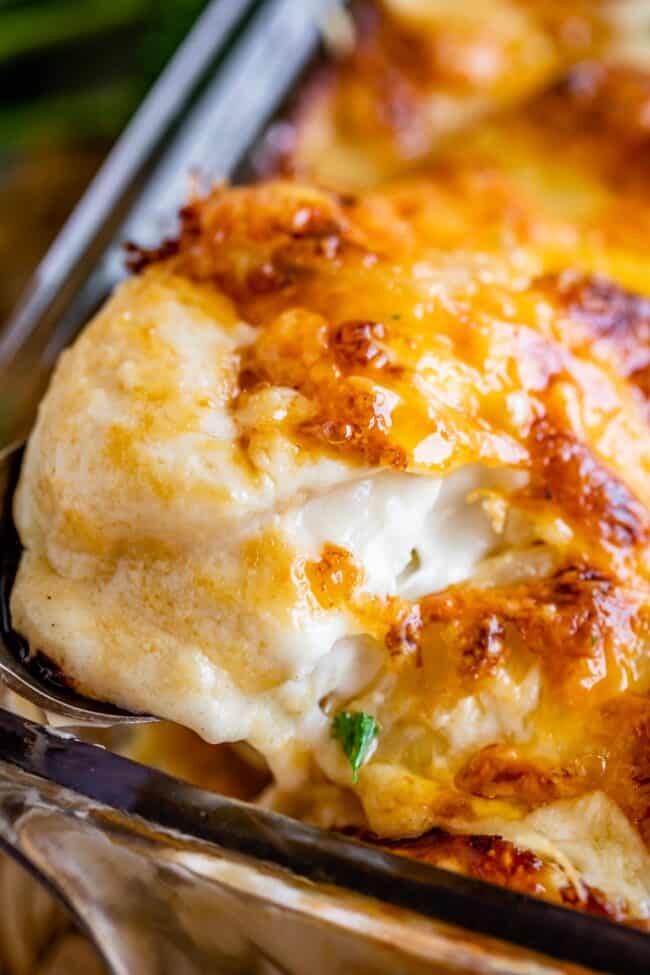 scalloped potatoes recipe with cheese topping being lifted out of the pan with a spoon.