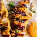 thai chicken satay on a skewer with peanut sauce on the side