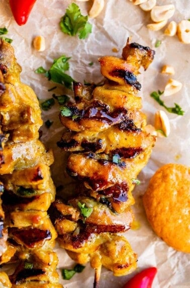 thai chicken satay on a skewer with peanut sauce on the side