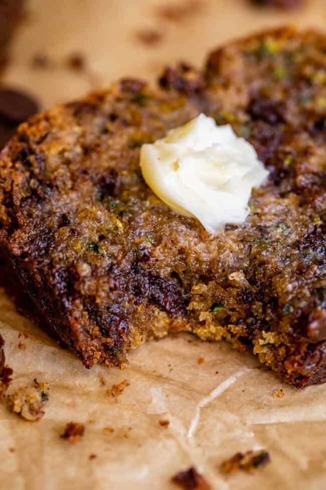 melting butter on zucchini bread slice with a bite taken out.